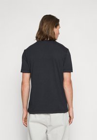 T-shirt preta de algodão com mangas curtas e decote redondo, apresentando um design liso e um corte descontraído, vista por trás.