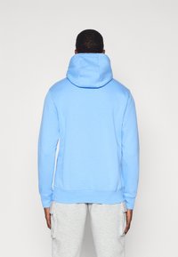 Felpa blu chiaro con un cappuccio grande e regolabile, maniche lunghe, polsini e vita a coste. Materiale in cotone testurizzato.