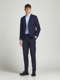 Navy check suit with tailored fit, single-breasted jacket, and notch lapels, paired with a light blue dress shirt and dark shoes.
