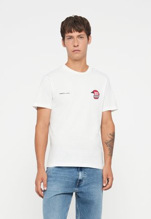 T-shirt en coton blanc avec un col rond, des manches courtes et un patch logo rouge avec des accents noirs sur la poitrine gauche.