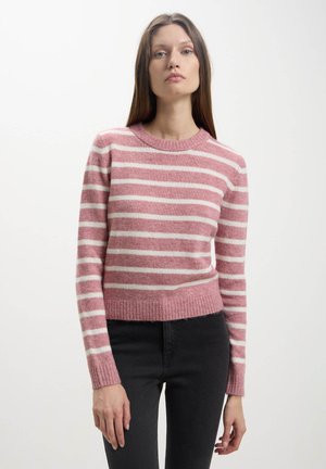 Un pull rayé rose et blanc avec un col rond, un ourlet et des poignets côtelés, fabriqué à partir d'un tissu doux et texturé. Assorti à un pantalon noir.