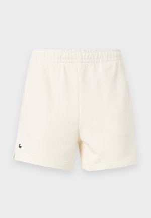 Off-white casual shorts with elastic waistband and small green crocodile logo on lower left leg.
