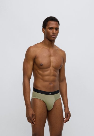 Herren-Slips aus olivgrünem Stoff mit einem schwarzen elastischen Bund. Verfügt über ein Logo auf der Vorderseite, eine enganliegende Form und eine glatte Textur.