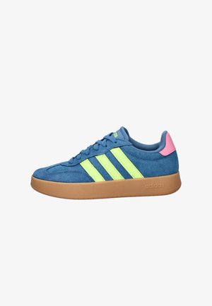 Blauwe suède Adidas-sneaker met neon gele strepen, roze hieltab, gummy zool en vetersluiting, zijaanzicht op witte achtergrond.