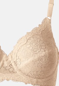 Nude kleur kanten bh met bloemenpatronen, een zachte textuur, golfranden en een kleine strikaccent aan de zijkant van de band.