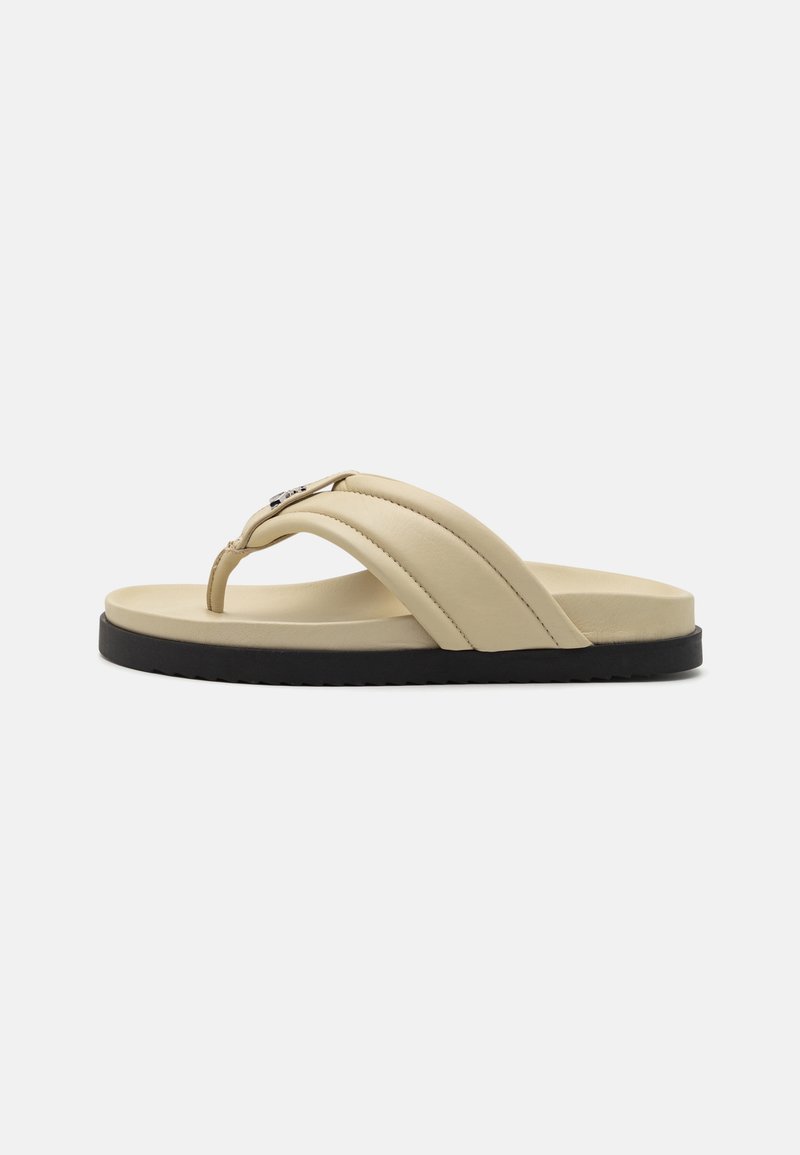Beige faux skinnflip-flops med to brede remmer og en tynn tåstang. Har såle i svart gummi og metallisk detalj på remmen.
