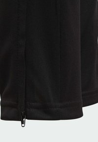 Pantalones cortos deportivos negros con una textura suave, cierre de cremallera en el dobladillo y un sutil diseño acanalado a lo largo del costado.