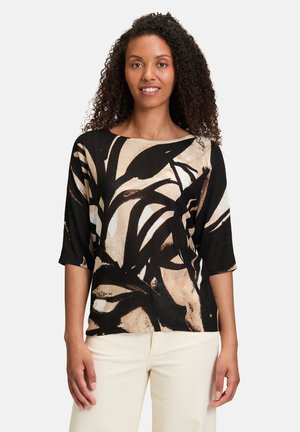 Losse zwarte top met beige en bruine abstracte bladerenpatronen, met driekwartmouwen en een wijde nek. Zachte textuur.