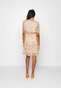 Vestido floral com mangas curtas, cintura franzida e bainha com folhos. Apresenta uma palete de cores pastel com pequenas flores em rosa, amarelo e verde.