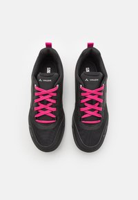 Des chaussures de sport noires avec des lacets roses. Tige en mesh avec des accents synthétiques et une semelle en caoutchouc. Possède des languettes au talon pour un enfilage facile.