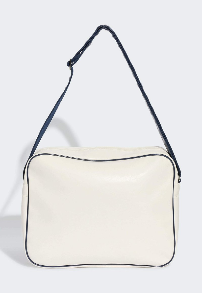 Borsa a tracolla rettangolare bianca con piping nero e tracolla regolabile in blu scuro, esposta su uno sfondo chiaro e uniforme.