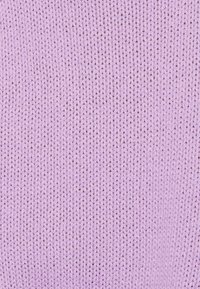 Gros plan sur un tissu tricoté de couleur lavande montrant des rangées verticales détaillées et de petits points uniformément espacés.