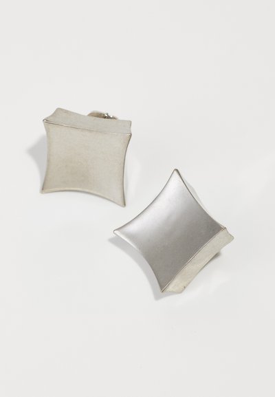 Gemelli da polso metallici argento a forma di quadrati morbidi con angoli arrotondati, caratterizzati da una finitura liscia e leggere variazioni di texture.
