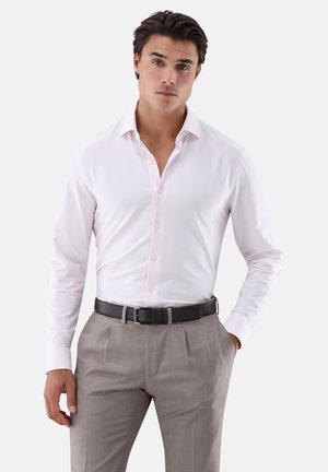 Helles rosa Hemd mit dezentem Streifenmuster, langen Ärmeln und klassischem Kragen, kombiniert mit hellgrauen Hosen und einem schwarzen Gürtel.