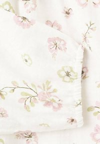 Belo blago z vzorcem cvetja z rožnatimi in zelenimi cvetovi. Tekstura je videti mehka in lahka. Vidna je podrobnost elastičnega traku.