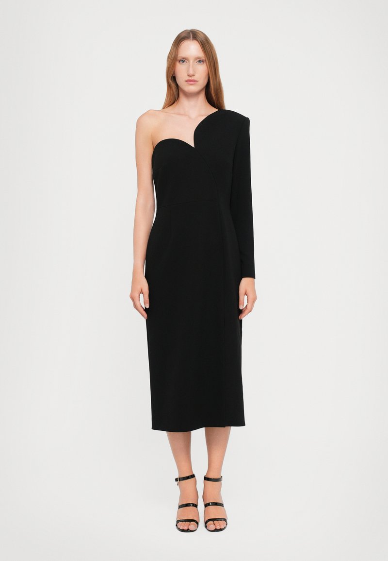 Crna haljina s jednim ramenom koja ima uski kroj, do koljena je i glatke je teksture. Minimalistički dizajn s asimetričnim izrezom.