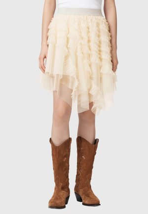 Kremowa, warstwowa spódnica z tiulu do kolan z falbanami, zestawiona z brązowymi, zamszowymi kowbojkami z haftem.