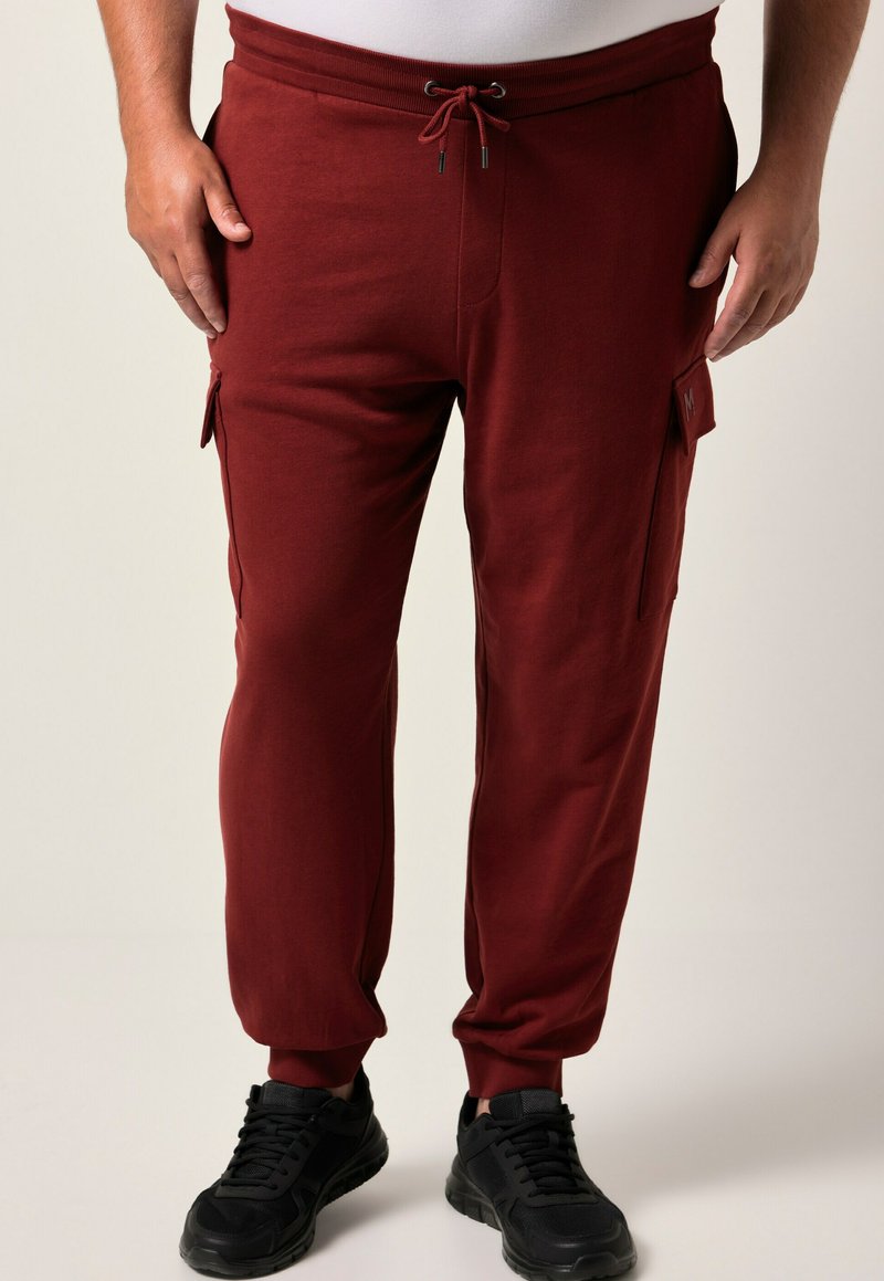 Burgunderfarbene Jogginghosen aus Baumwollmischung, mit einem Kordelzugbund, seitlichen Cargo-Taschen und schmal zulaufenden Säumen, kombiniert mit schwarzen Sneakers.