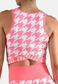 Top atlético sin mangas con un patrón de tejido de gallo rosa y blanco y el texto "ENDLESS" en el dobladillo, usado por una persona vista desde atrás.