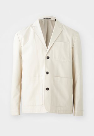 Veste en coton beige avec un col cranté, trois boutons noirs et deux poches avant. Elle dispose d'une poche poitrine et de manches longues.