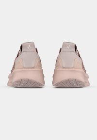 Pár růžových tenisek Adidas zobrazených zezadu na bílém pozadí, zdůrazňujících design podrážky a paty.