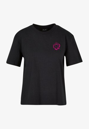 Camiseta negra de manga corta con cuello redondo y pequeño gráfico rosa en el lado izquierdo del pecho que parece una calavera estilizada o una forma abstracta.