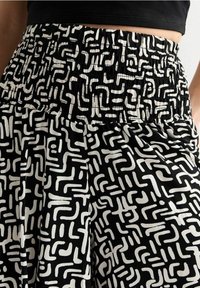 Jupe taille haute noir et blanc avec motif géométrique abstrait et taille élastiquée froncée, portée avec un haut noir.