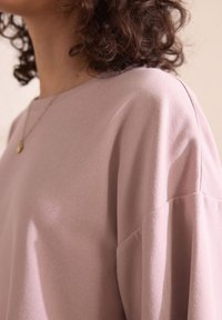 Top in tessuto testurizzato rosa chiaro con scollatura rotonda e spalle drop. Design semplice con un aspetto morbido e drappeggiato.