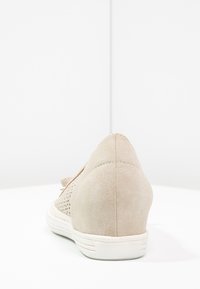 Chaussure compensée en daim beige avec côtés perforés et semelle en caoutchouc blanche, vue de dos sur fond blanc.