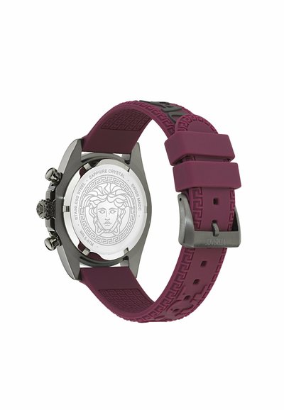 Sidabrinis nerūdijančio plieno laikrodis su skaidriu ciferblato dangčiu, violetiniu guminiu dirželiu su tekstūruotu raštu ir metaline sagtimi.