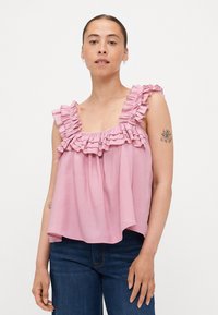 Lys rosa ermeløs topp med volangstropper og løs passform. Laget av myk tekstil, med et lagdelt volangdetalj over brystet.