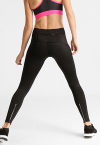 Leggings atléticos negros con cintura alta, que cuentan con un bolsillo trasero y cremalleras en los tobillos. Textura suave y tejido elástico para mayor comodidad.