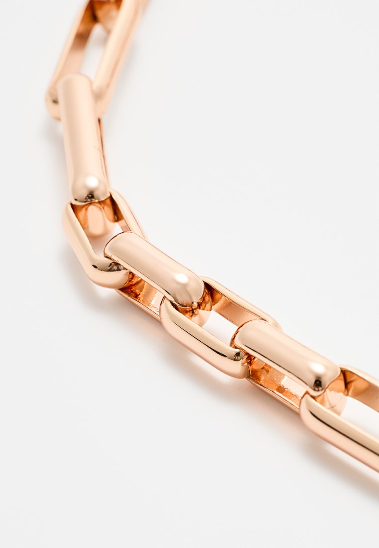 Primo piano di catene rettangolari di colore rosato lucido collegate su uno sfondo bianco.