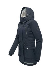Tmavomodrá bunda s plyšovou podšívkou v kapuci, so zipsovými vreckami a nastaviteľnými šnúrkami v páse. Charak terizuje ju hladká textúra a praktický dizajn.