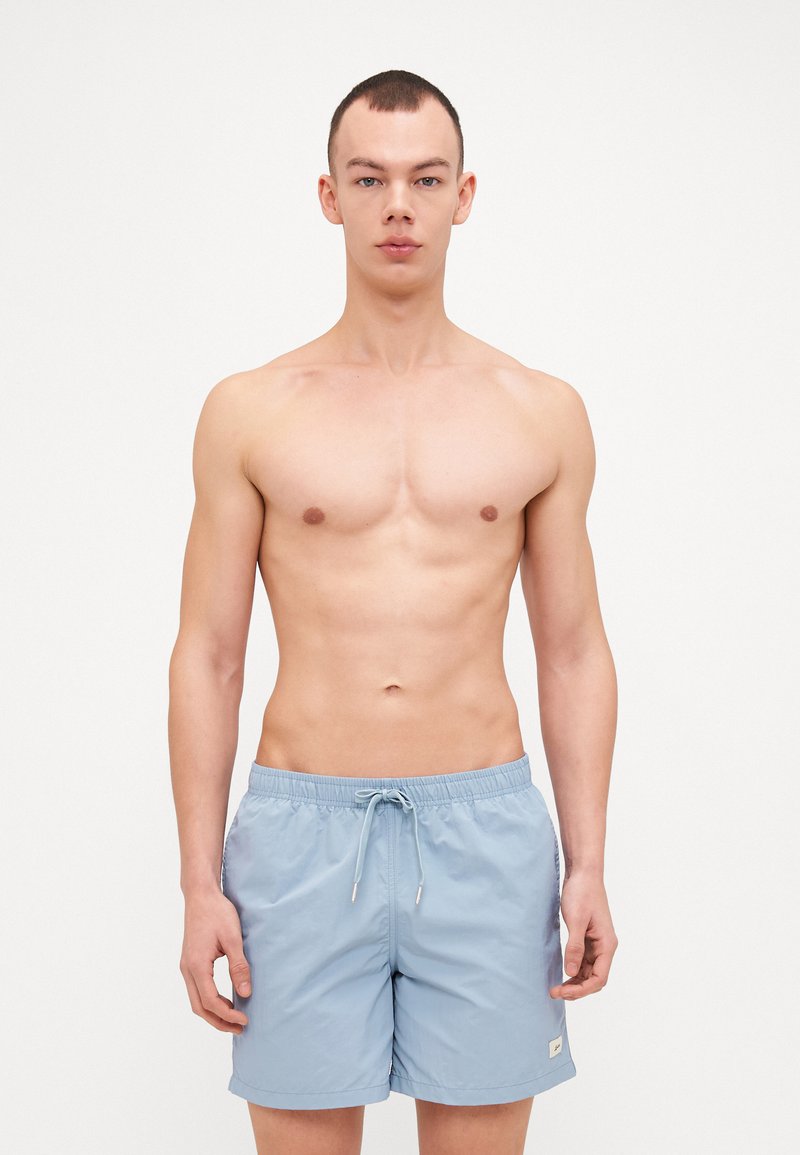 Lichtblauwe zwemshorts van lichtgewicht stof, met een elastische tailleband, trekkoord en een klein logo-opdruk aan de zijkant.