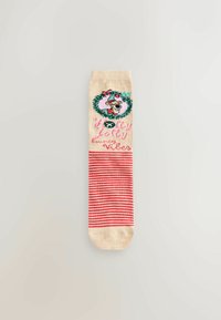 Beige socks with red stripes, featuring a green wreath design and a cartoon character with a Santa hat. Text reads "Holly Jolly Vibes."