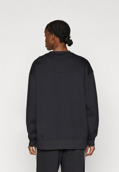 Μαύρο φούτερ με άνετη γραμμή, στρογγυλή λαιμόκοψη και κατεβασμένους ώμους. Ομαλή υφή με ριμπ μανσέτες και τελείωμα.