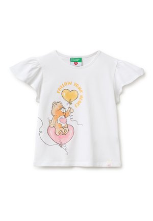 Biała koszula z krótkim rękawem z bufkami, przedstawiająca niedźwiedzia trzymającego żółte i różowe baloniki w kształcie serca oraz napis „Podążaj za swoim sercem.”