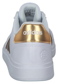 Białe sneakersy z złotymi akcentami, teksturowana gumowa podeszwa i siateczkowe wykończenie. Posiadają logo marki na pięcie oraz wzorzystą boczną panel.