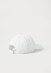 Bela bejzbolaška kapa iz bombaža s ukrivljenim šiltom, nastavljivim tekstilnim trakom na hrbtni strani ter šivinimi odprtinami za prezračevanje.