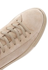 Beige Wildlederschuhe mit einer glatten Zehenkappe, Mesh-Seitenpaneelen und flachen Schnürsenkeln. Die Sohle ist hell gefärbt und strukturiert für besseren Halt.