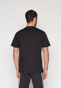 Svart kortärmad T-shirt med rund hals, tillverkad av bomull. Enkel design, inga mönster, med en jämn textur och en avslappnad passform.