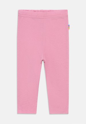Leggings rosa semplici di dimensioni per bambini piccoli con una piccola etichetta a righe multicolori sull'anca destra, mostrati distesi su uno sfondo bianco.