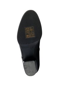 Black rubber shoe sole with a textured pattern, featuring a metallic heel accent and printed instructions in yellow and white.