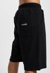 Black men's shorts made of soft fabric, featuring a side pocket and a logo patch. Straight cut with an elastic waistband.