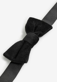 Cravattino nero realizzato in tessuto morbido e testurizzato con una fascia in raso liscia. Il papillon presenta una finitura leggermente pelosa e un nodo centrale come dettaglio.