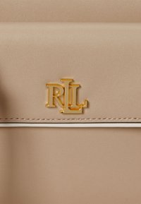 Geantă bej cu o textură netedă, logo-ul auriu "RL" și cusături albe de accent pe margini.