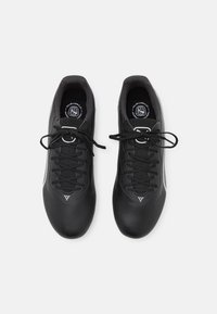Scarpe sportive nere con una tomaia liscia e testurizzata, dotate di lacci neri, colli imbottiti e accenti bianchi sui lati.