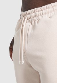 Beige Sweatpants mit einem gerippten elastischen Bund und Kordelzug. Weicher Stoff mit lockerer Passform und seitlichen Taschen.