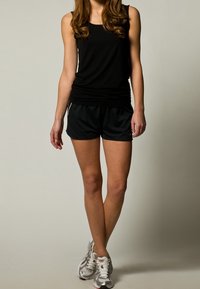 Débardeur noir et shorts de sport noirs à coupe décontractée, associés à des chaussures de course argentées. Textures lisses et design basique.